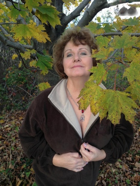 Starsza kobieta Busty Bliss eksponuje swoje duże naturalne cycki pod drzewem jesienią