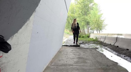 Blond meisje Jenna Lovely trekt haar broek naar beneden om op een stuk beton te plassen