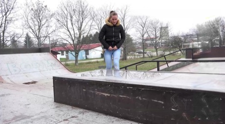 Den hvide pige Naomi Bennet tisser i en vandpyt i en skatepark om dagen.