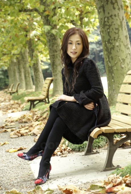穿着黑色衣服和丝袜的全副武装的日本青少年模特在公园里。