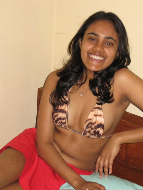 Indisches Mädchen mit einem schönen Lächeln zeigt ihre Brüste auf einem Bett