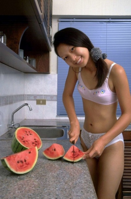 Charmanter asiatischer Teenager zieht Spitzenunterwäsche aus, während er eine Wassermelone isst