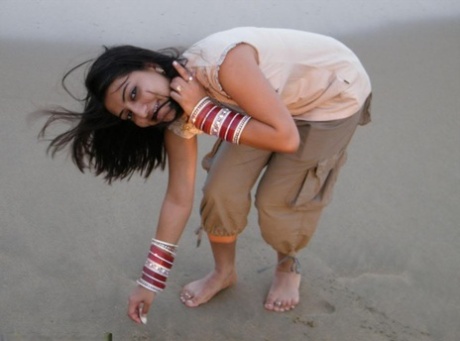 Smuk indisk pige går barfodet på stranden under ikke-nøgen action