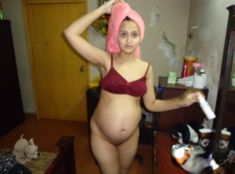 Pregnant Indian girl moisturizes after a shower before getting dressed