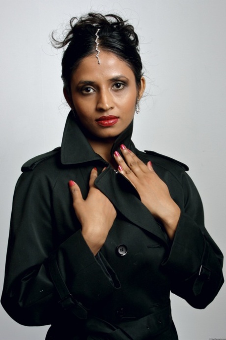Vakker indisk kvinne kaster frakken for å stå modell i undertøy og strømper.