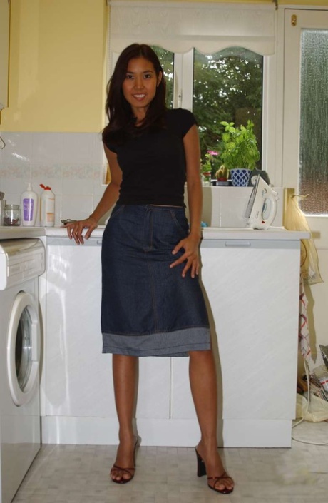Une amatrice asiatique aux longues jambes se déshabille entièrement sur le comptoir de sa cuisine.