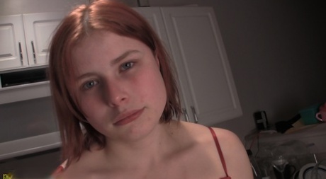 Young redhead Dahlia pisses into a measuring cup while in a kitchen