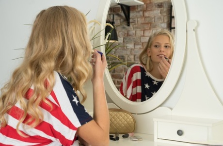 Jonge blonde Amy doet haar make-up in een spiegel voordat ze naakt wordt op een stoel