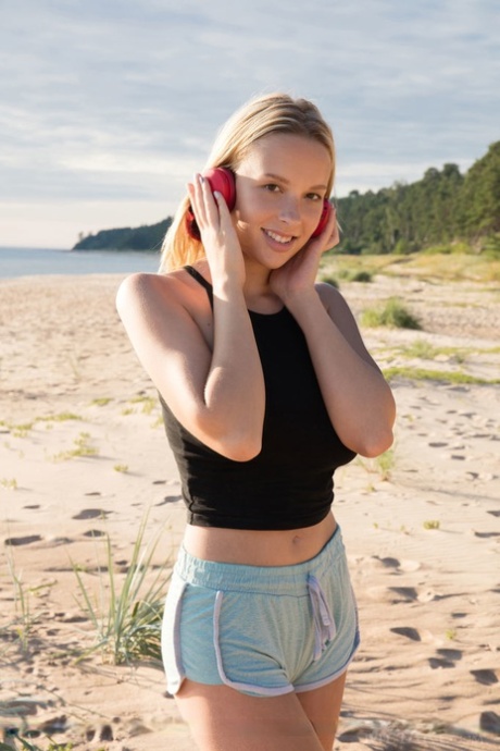 Junge Blondine mit tollen Titten präsentiert ihre glatte Muschi am Strand