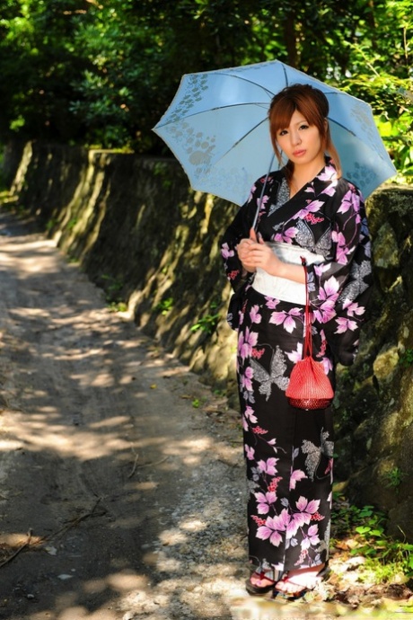 Japansk rödhårig kvinna med parasoll på promenad i kimono