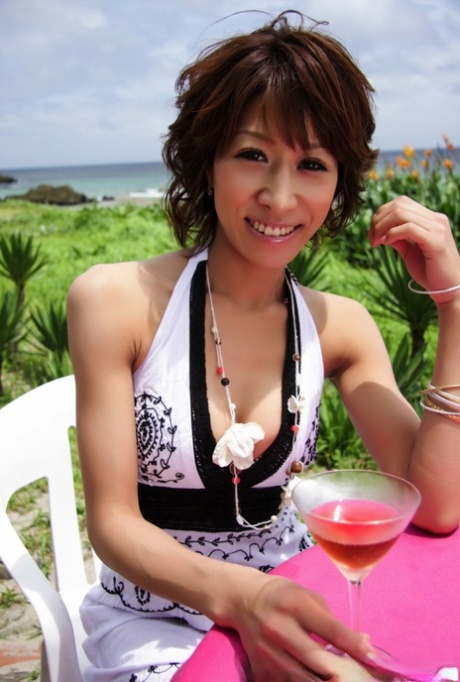 Симпатичная японка демонстрирует свое декольте за коктейлем у океана