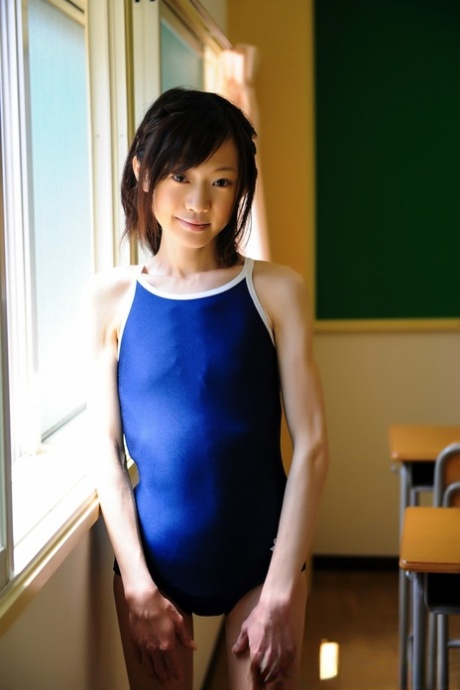 Pequena modelo japonesa não nua em fato de banho na mesa da escola
