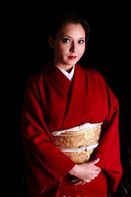 Japansk kvinde har røde læber, mens hun fremstiller en kniv i traditionelt tøj