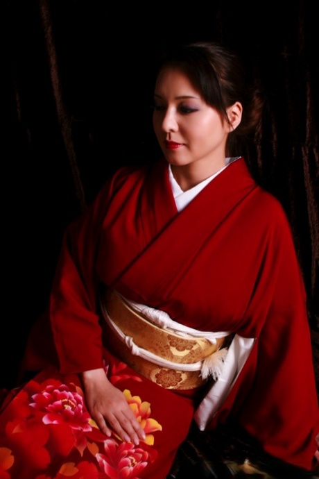 Japanische Frau trägt rote Lippen, während sie in traditioneller Kleidung ein Messer herstellt