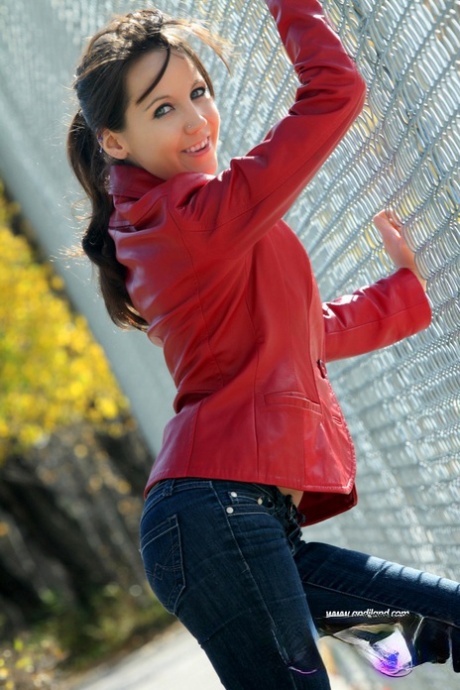 La teenager amatoriale Andi Land mostra le sue piccole tette e la sua figa contro una recinzione a catena