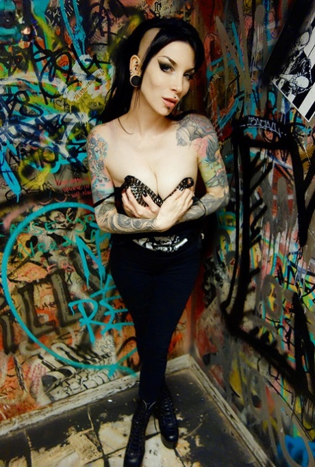 Une fille gothique, Razor Candi, se déshabille avec des bottes dans une salle de bain pleine de graffitis.
