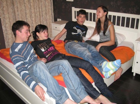 Unge brunetter og deres kærester har firersex oven på en seng
