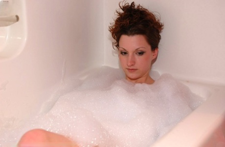 Den rødhårede MILF-en Kendall Blaze slår ut håret mens hun bader naken i boblebad