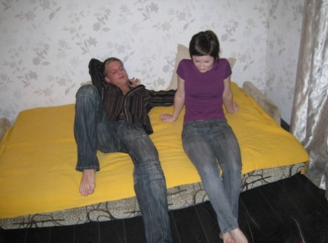 ベッドで3Pする前にジーンズを脱ぐティーンエイジャーの女の子とその男友達。