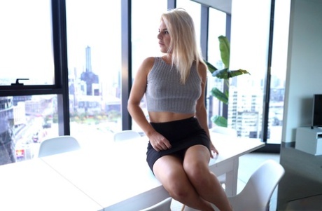 Den blonde jenta Ophelia Rose viser frem den saftige rumpa under sex på et bord ved et vindu.