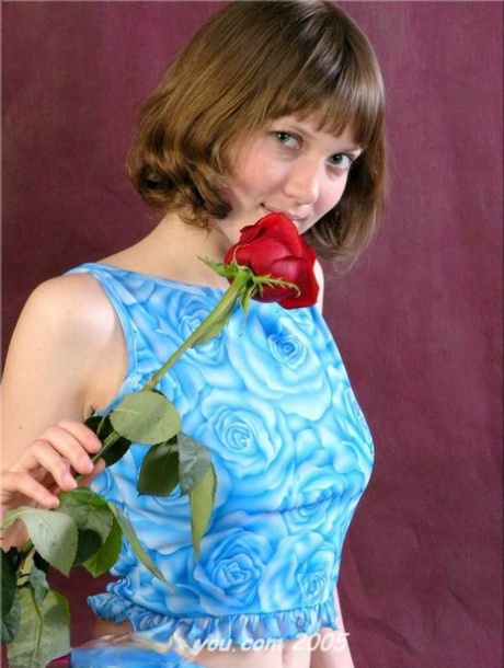 Urocza nastolatka Anabell trzyma samotną czerwoną różę podczas zdejmowania ubrania