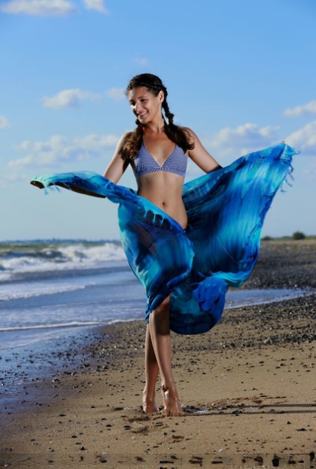 Tienermeisje Rosella speelt met vlechten voordat ze haar bikini uittrekt op een strand