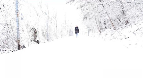 Kaukasisches Mädchen Esperansa zieht ihre Jeans herunter, um auf den schneebedeckten Boden zu pinkeln