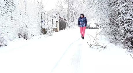 Kaukasisches Mädchen Henna zieht rosa Hosen herunter, um auf eine schneebedeckte Straße zu pinkeln