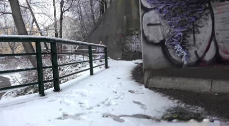 Caucasian girl Gianna Ray ducks under an overpass to take a pee in the winter