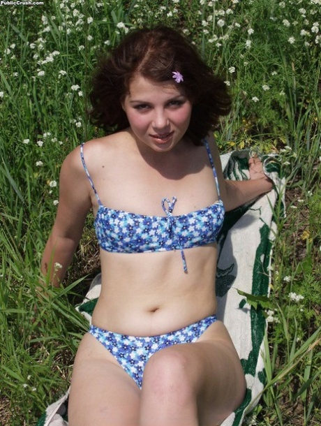 Jong uitziend meisje trekt haar bikini uit om naakt te gaan temidden van wilde bloemen