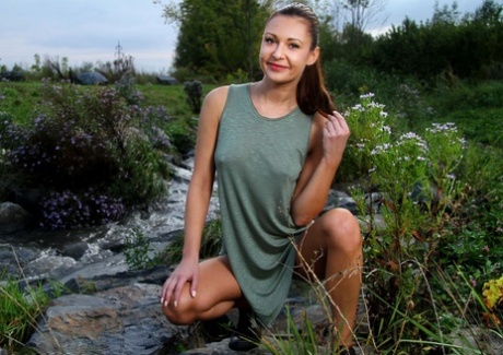 Teen model Kara Rosemary lifts up a dress while on rocks by a stream