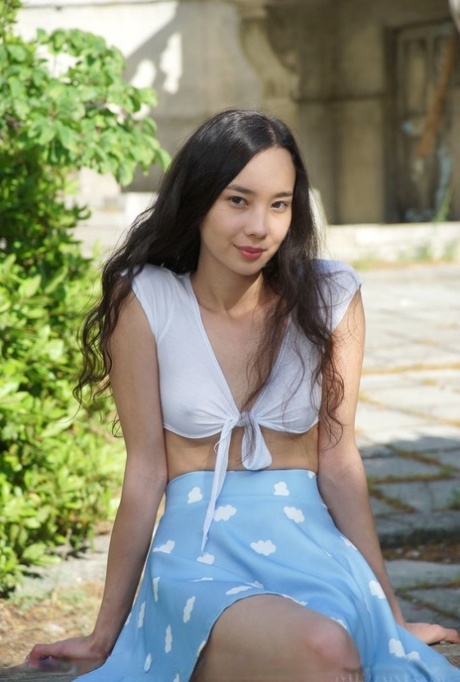 Asiatiska tonårstjejen Djessy har en kjol utan trosor innan hon poserar naken på en uteplats