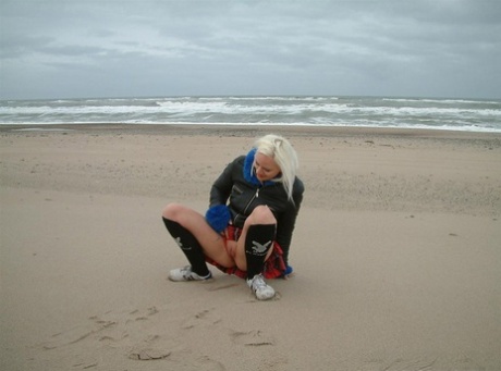 Blondes Mädchen pisst an den Strand und auch auf das Dünengras