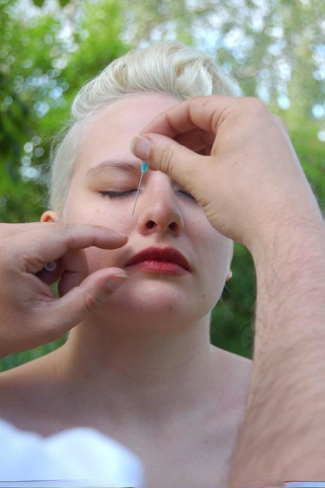 Blonde Frau mit roten Lippen beim Nadelspiel im Hinterhof