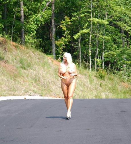 La rubia tetona Karen Fisher se pasea desnuda por una carretera asfaltada antes de masturbarse