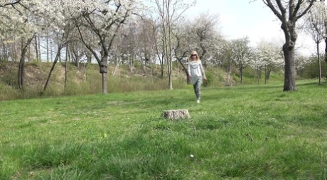 A rapariga loira Debora senta-se num cepo num parque enquanto mija