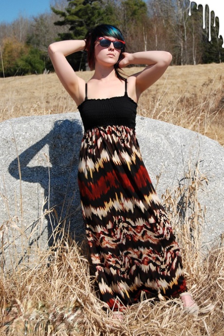 Teen-Amateurin Sabrina Squirts schlüpft oben auf einem Felsbrocken in einem Feld aus ihrem Kleid
