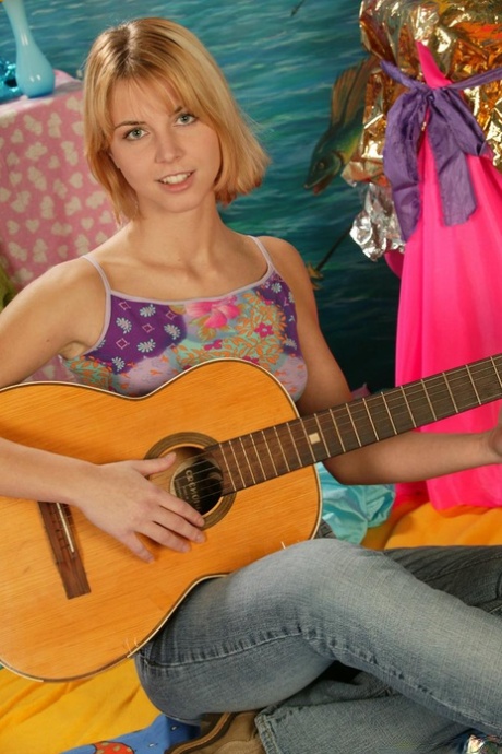 Une adorable adolescente joue de sa fente étroite après avoir gratté sa guitare avec des bottes.