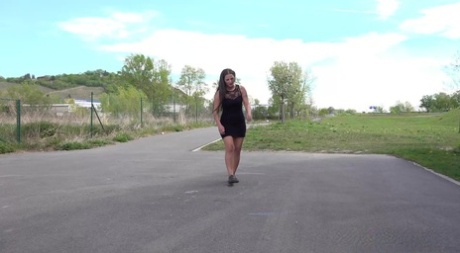 Brunette teen Nicolette Noir takes a badly needed pee on a paved road