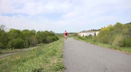Den kaukasiska flickan Amanda Hill pissar på en asfalterad väg när hon är ute och joggar
