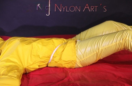 Fair skinned female is gagged and restrained in yellow nylon rain wear