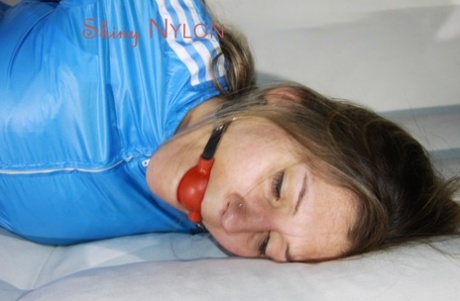 White girl is left ball gagged and hogtied on a futon in red nylon pants