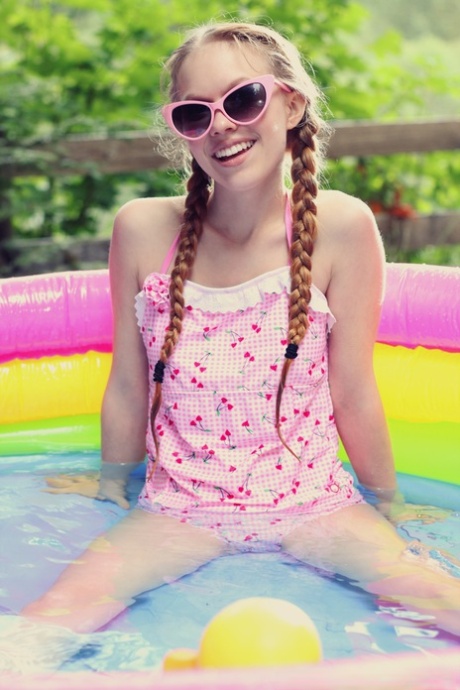 Adorable teen Dolly Little tugs on her braided pigtails in a blowup pool