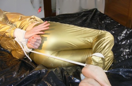 Caucasian female is left gagged and tied up in gold rainwear