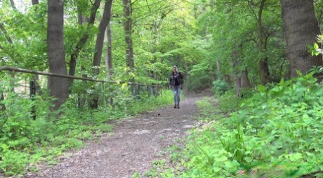 Das nette Mädchen Barbe pinkelt in Jacke und Brille auf einen Waldweg