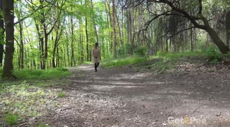 Caucasian girl Esperansa takes a pee on dried leaves in a public park