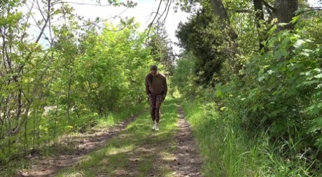 Wit meisje met bril trekt haar legging naar beneden om te plassen op een pad in het bos