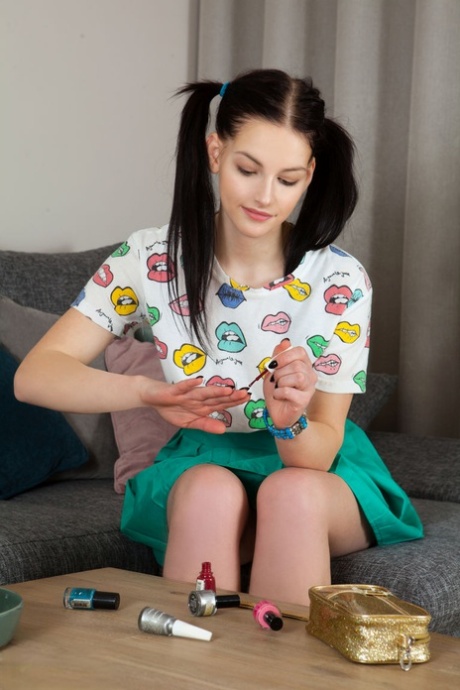 Cute teen Vienna does her nails before modelling completely naked on a sofa