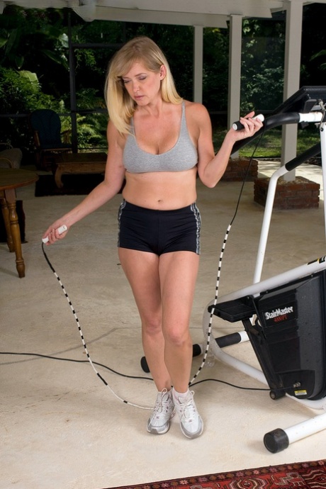 Busty blond MILF exponerar sina stora naturliga bröst när hon tränar på gymmet