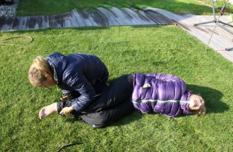 Blonde lesbian is tied up and soaked on a lawn in winter clothing